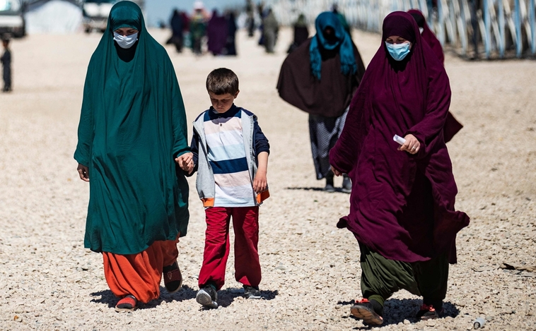 Beberapa wanita dan seorang anak berjalan melewati kamp pengungsi Al Roj